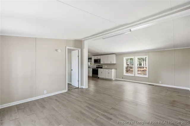 a view of empty room with wooden floor and window