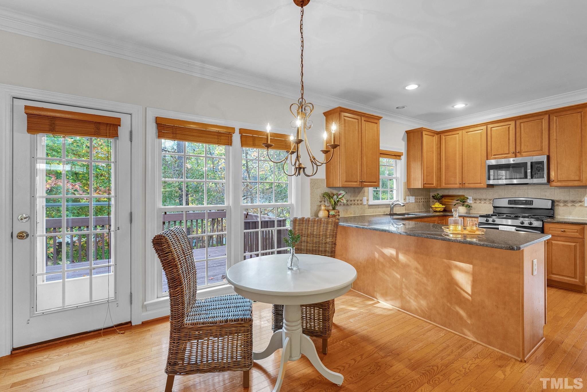 8409 Aptos Court Raleigh, NC 27613 - Photo 19 of 46 a kitchen with granite countertop a table chairs microwave and cabinets