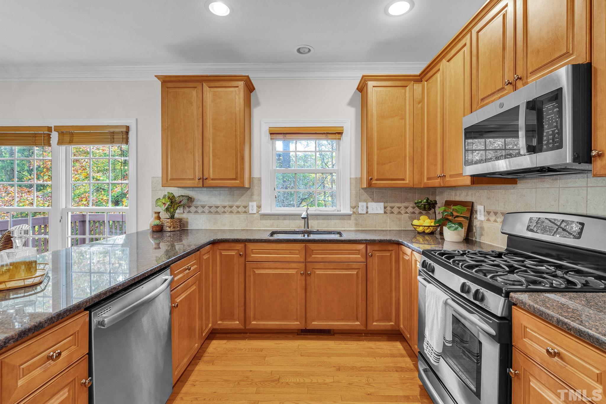 8409 Aptos Court Raleigh, NC 27613 - Photo 23 of 46 a kitchen with stainless steel appliances granite countertop a stove a sink and a microwave