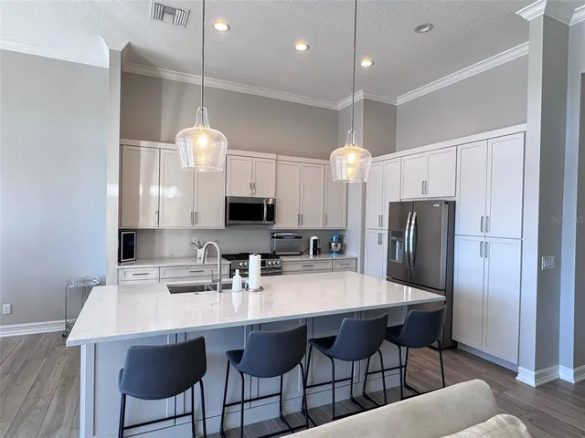 a living room with stainless steel appliances kitchen island granite countertop a couch a stove a sink and a refrigerator