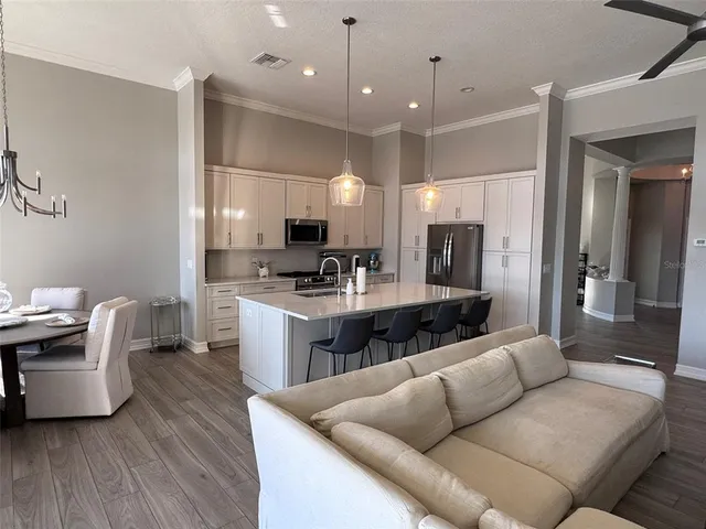 a living room with stainless steel appliances kitchen island granite countertop a couch a stove a sink and a refrigerator