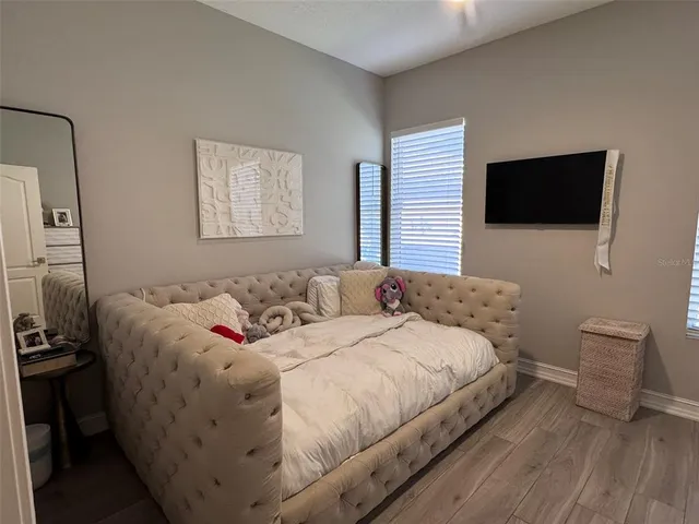 a bedroom with a bed a tv and wooden floor
