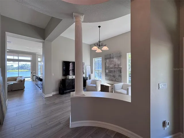 an empty room with wooden floor windows and fan