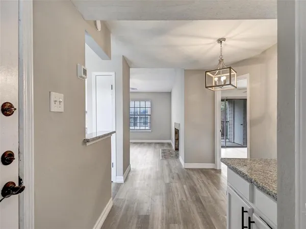 a view of a hallway with wooden floor and a kitchen