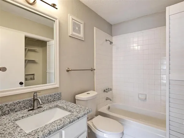 a bathroom with a granite countertop sink toilet mirror and shower