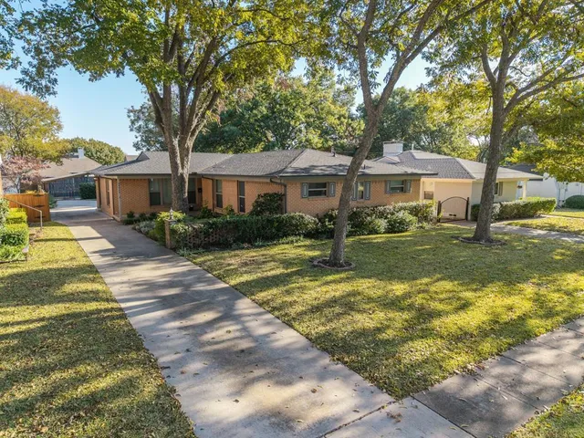 a front view of a house with a garden and trees