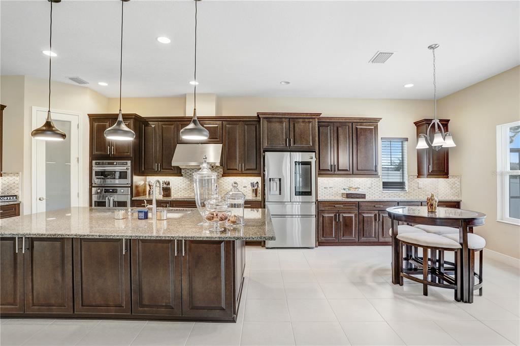 32450 Talimena Loop Wesley Chapel, FL 33543 - Photo 18 of 68 a kitchen with stainless steel appliances kitchen island granite countertop a sink refrigerator and cabinets