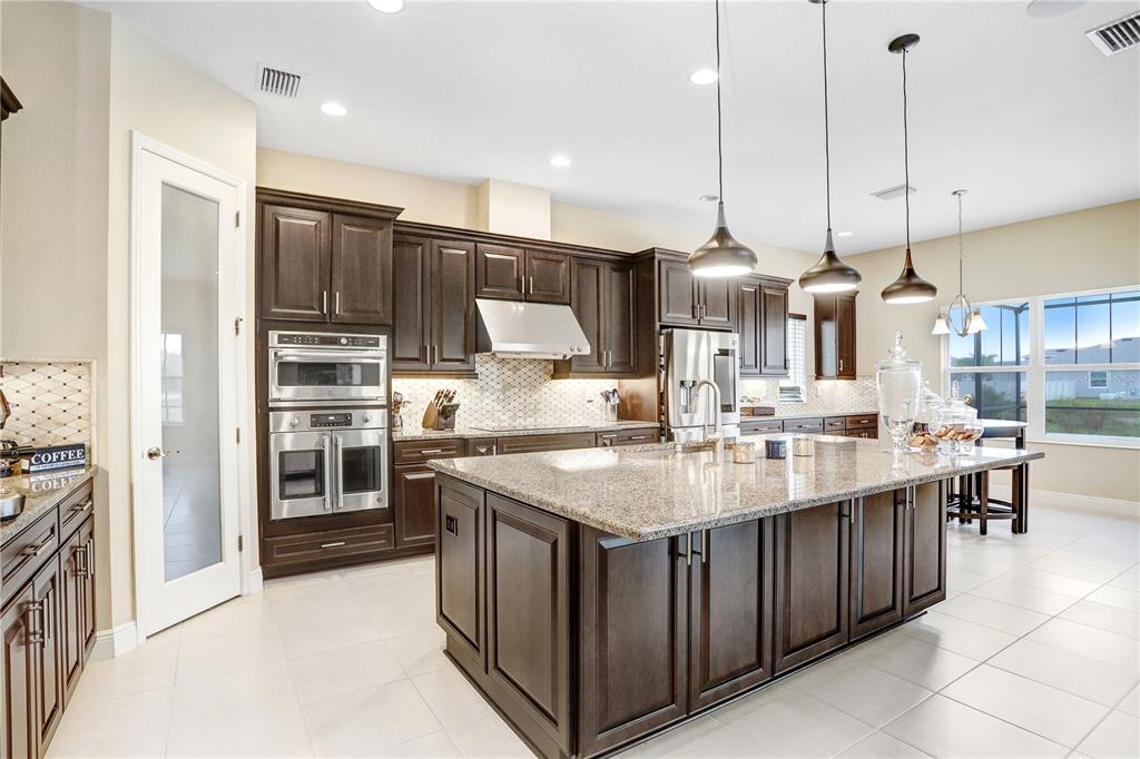 32450 Talimena Loop Wesley Chapel, FL 33543 - Photo 19 of 68 a kitchen with stainless steel appliances granite countertop a sink a stove and a refrigerator