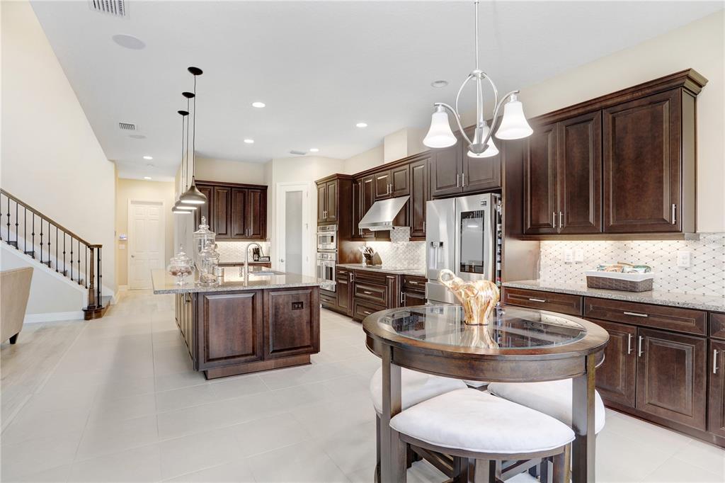32450 Talimena Loop Wesley Chapel, FL 33543 - Photo 21 of 68 a kitchen with kitchen island granite countertop a sink a stove a refrigerator cabinets and chairs