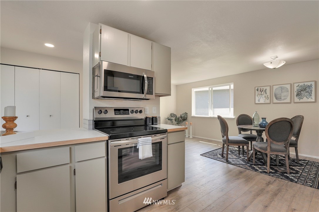 1017 234th Place Southwest Bothell, WA 98021 - Photo 9 of 28 a kitchen with stainless steel appliances a stove top oven a sink dishwasher a refrigerator with white cabinets and wooden floor