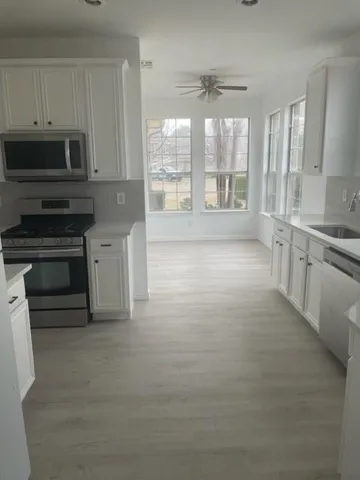 a large white kitchen with granite countertop a stove a sink and a granite counter tops