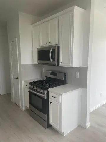 a kitchen with white cabinets and stainless steel appliances