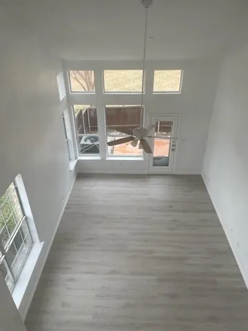 a view of empty room with wooden floor and fan