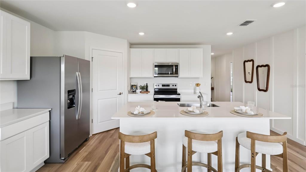 4694 Kona Circle Spring Hill, FL 34608 - Photo 7 of 29 a kitchen with stainless steel appliances a dining table chairs refrigerator and microwave