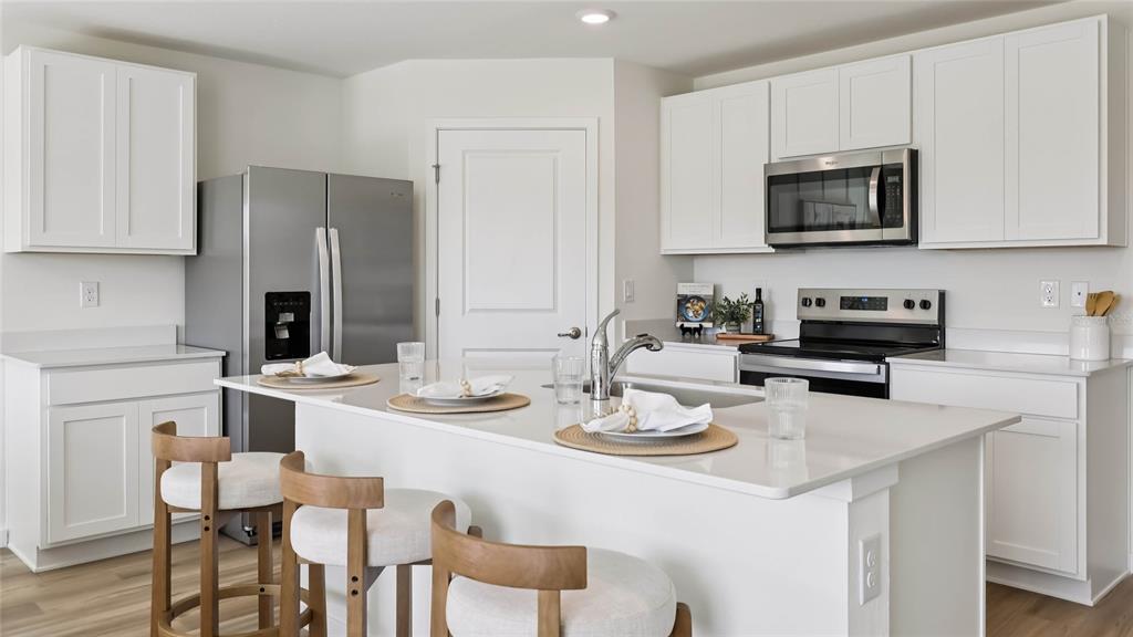 4694 Kona Circle Spring Hill, FL 34608 - Photo 8 of 29 a kitchen with stainless steel appliances kitchen island granite countertop a table chairs microwave and cabinets