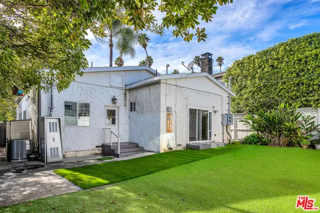 a view of a white house with a big yard and large tree