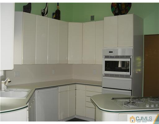 22 Evan Drive Morganville, NJ 07751 - Photo 7 of 14 a kitchen with stainless steel appliances a sink a stove and white cabinets