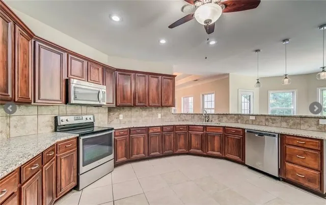 a large kitchen with stainless steel appliances granite countertop a sink dishwasher stove and cabinets