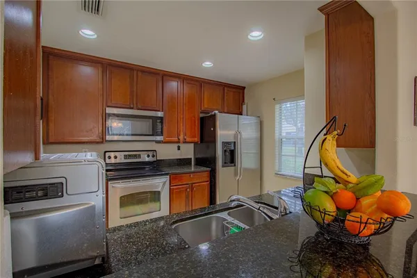 a kitchen with stainless steel appliances granite countertop a refrigerator and a stove top oven