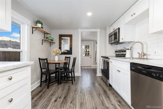 a kitchen with stainless steel appliances a dining table chairs microwave and sink