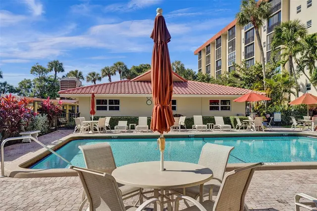 a patio with a table and chairs and potted plants