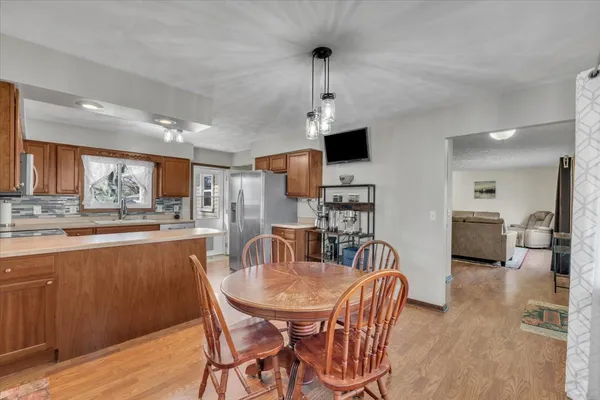 a view of a dining room and livingroom with furniture wooden floor a rug a fireplace and a chandelier