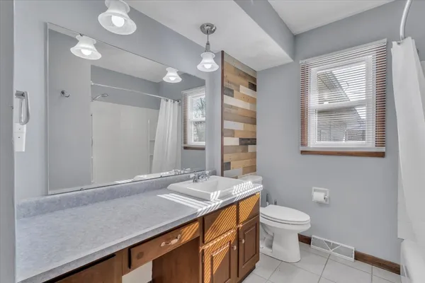 a bathroom with a sink a toilet a mirror and a window