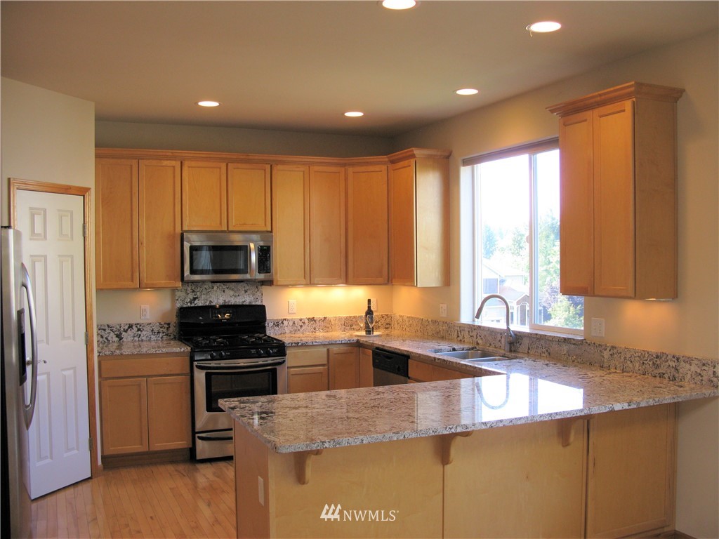 1219 187th Street Southeast Bothell, WA 98012 - Photo 13 of 39 a kitchen with kitchen island granite countertop a sink a counter top space appliances and cabinets