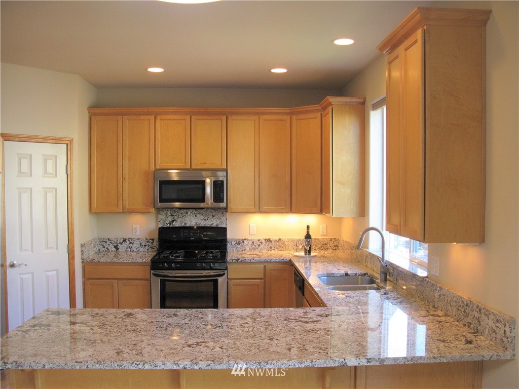 1219 187th Street Southeast Bothell, WA 98012 - Photo 14 of 39 a kitchen with kitchen island granite countertop a stove sink and cabinets