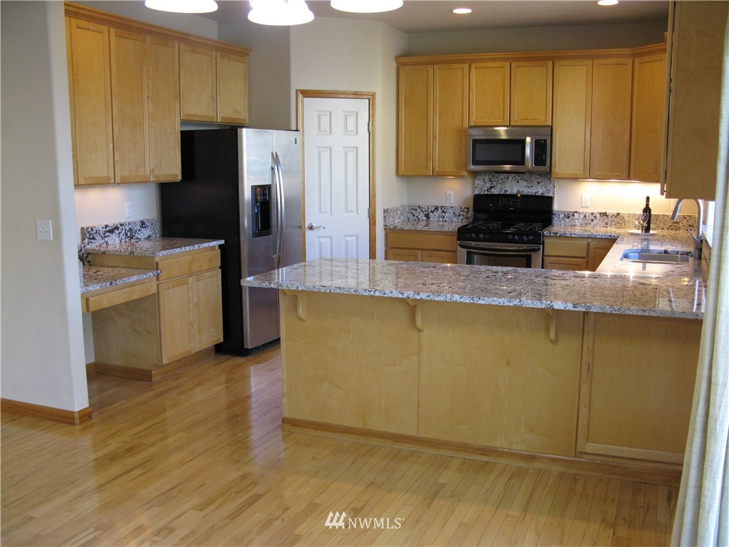 1219 187th Street Southeast Bothell, WA 98012 - Photo 15 of 39 a kitchen with stainless steel appliances granite countertop a refrigerator a stove top oven a sink and dishwasher