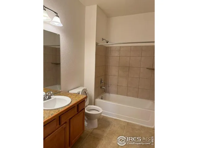 a bathroom with a granite countertop sink a toilet a mirror a bathtub and shower