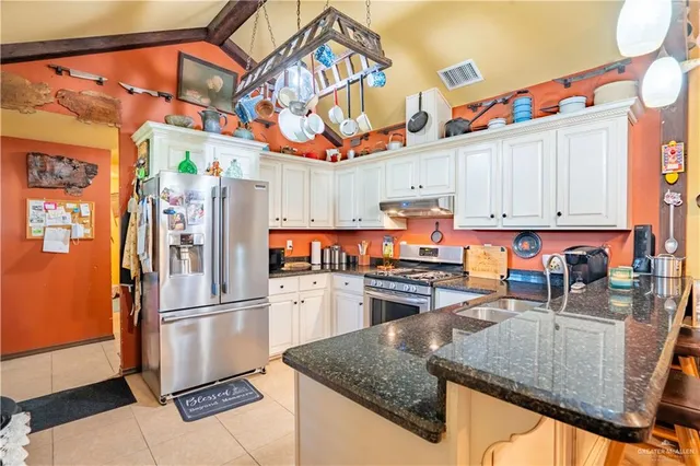 a kitchen with stainless steel appliances granite countertop a refrigerator a stove and a sink with wooden floor