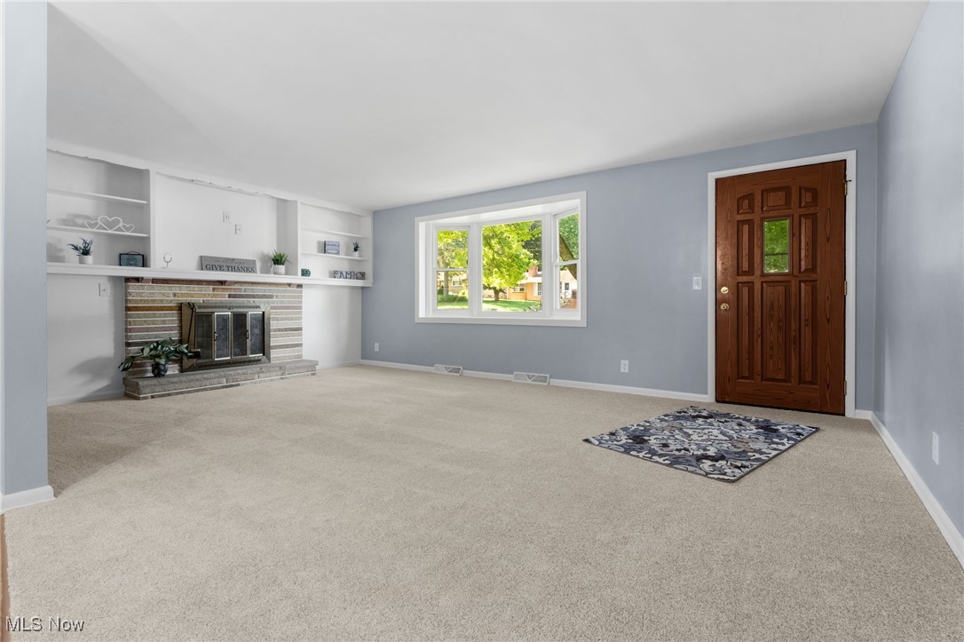 4895 3rd Street Northwest Canton, OH 44708 - Photo 5 of 27 Unfurnished living room with carpet flooring, a glass covered fireplace, and built in shelves