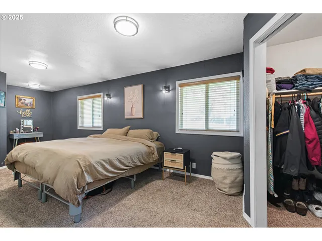 a spacious bedroom with a bed a dresser and a large mirror