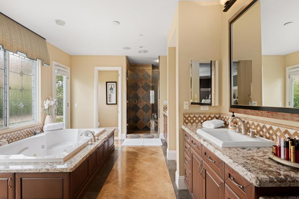 2541 Muirfields Drive Carlsbad, CA 92009 - Photo 22 of 58 a spacious bathroom with a granite countertop tub a sink and a large mirror