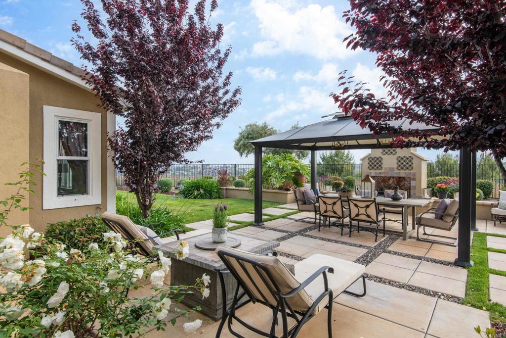 2541 Muirfields Drive Carlsbad, CA 92009 - Photo 40 of 58 a view of a patio with table and chairs under an umbrella with large trees