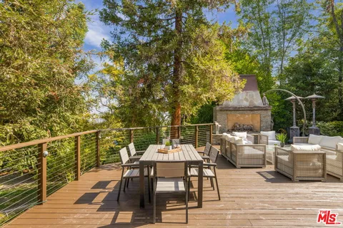 a view of a patio with couches table and chairs under an umbrella with wooden floor