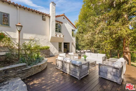 a view of a patio with couches table and chairs with wooden floor and fence