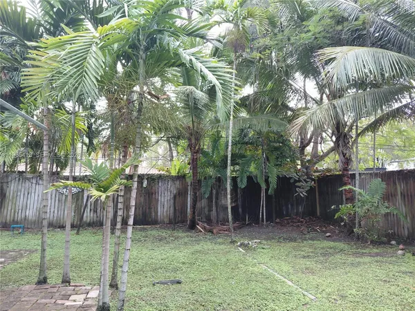 a backyard of a house with lots of plants and tree