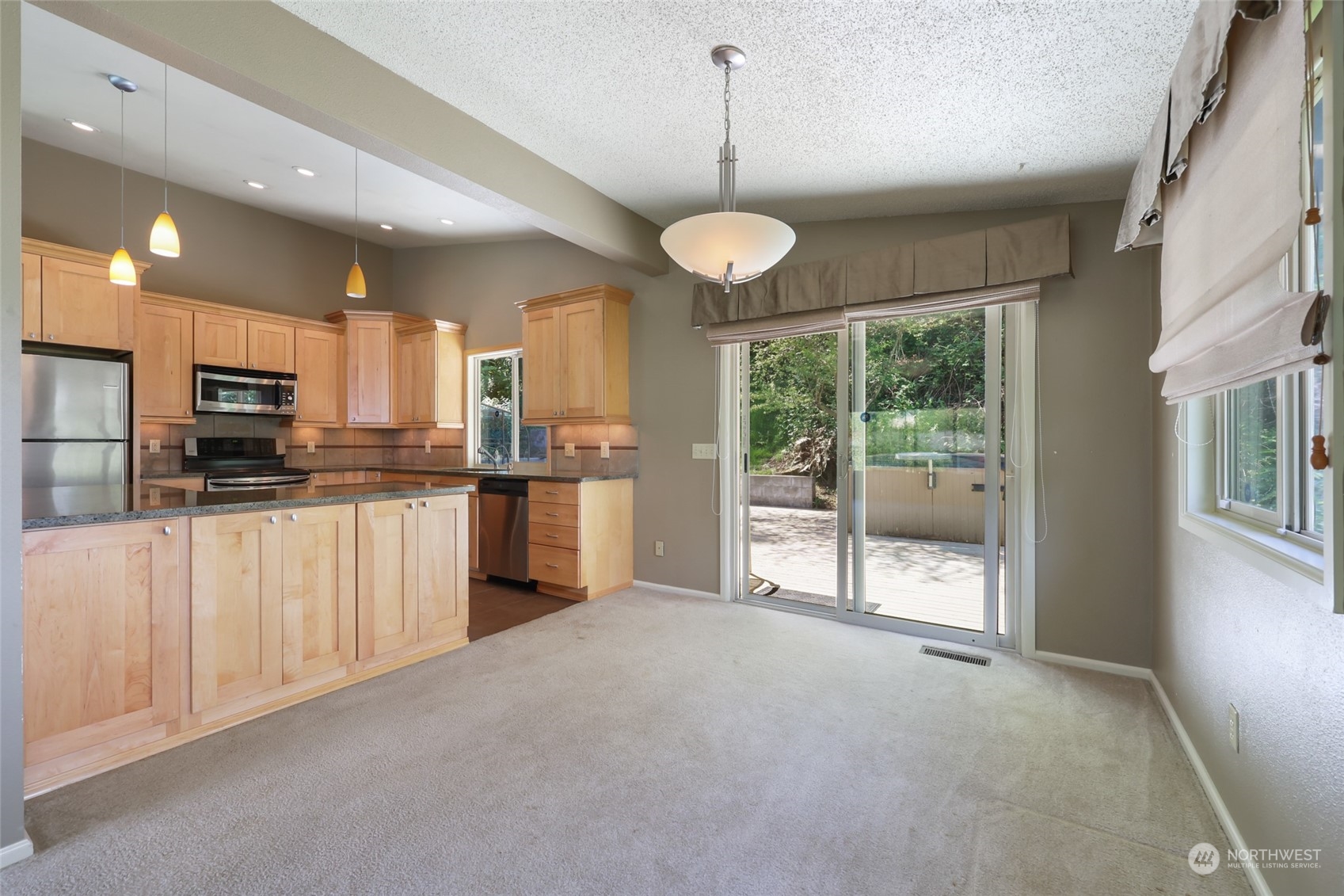 13835 17th Avenue Southwest Burien, WA 98166 - Photo 6 of 33 a open kitchen with stainless steel appliances kitchen island granite countertop a refrigerator a stove a oven with white cabinets and wooden floor