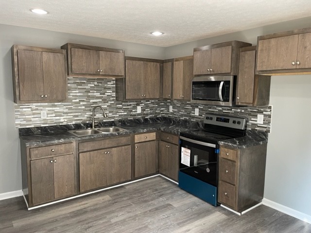 354 Riddle Lane Estill Springs, TN 37330 - Photo 2 of 7 a kitchen with stainless steel appliances granite countertop a stove a sink dishwasher and a microwave oven with wooden cabinets