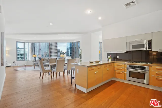 a large white kitchen with lots of counter top space and stainless steel appliances