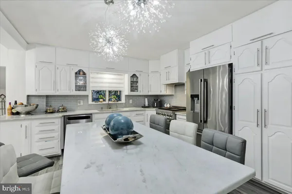 a kitchen with stainless steel appliances a stove a refrigerator a sink a stove a dining table and chairs