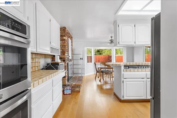 a kitchen with stainless steel appliances granite countertop white cabinets and a window