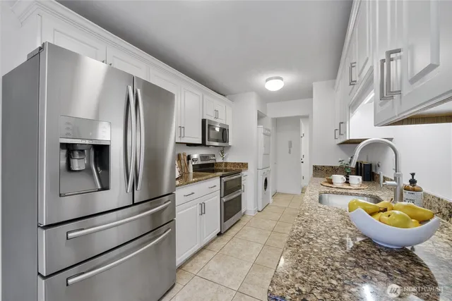 a kitchen with stainless steel appliances granite countertop a sink a stove and a refrigerator