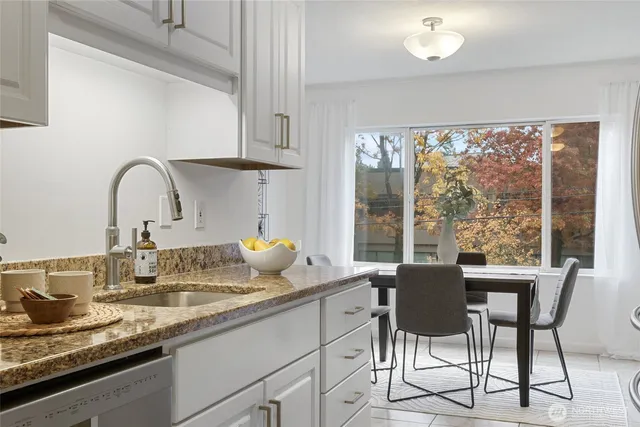a dining table with a large window and white kitchen