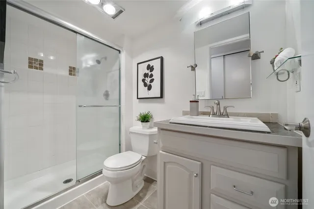 a bathroom with a granite countertop sink toilet a mirror and shower