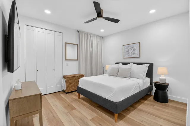 a spacious bedroom with a bed and large mirror with wooden floor