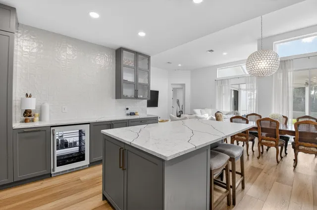 a large kitchen with stainless steel appliances kitchen island granite countertop a refrigerator a sink dishwasher a stove and white cabinets with wooden floor