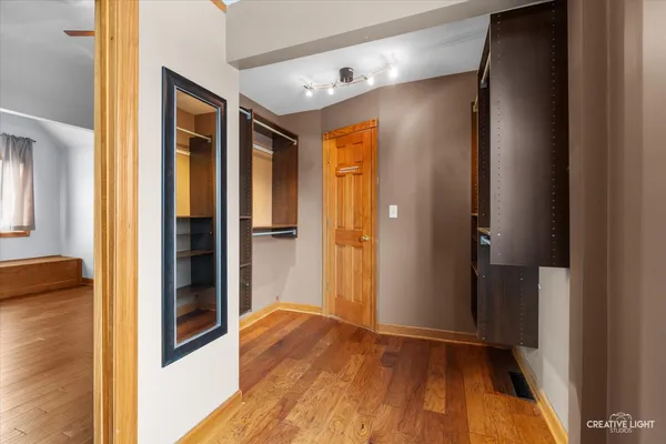 a view of an empty room with wooden floor and closet